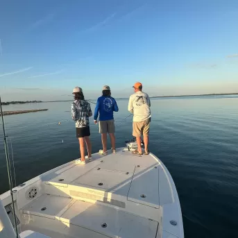three people fishing off bow of boat
